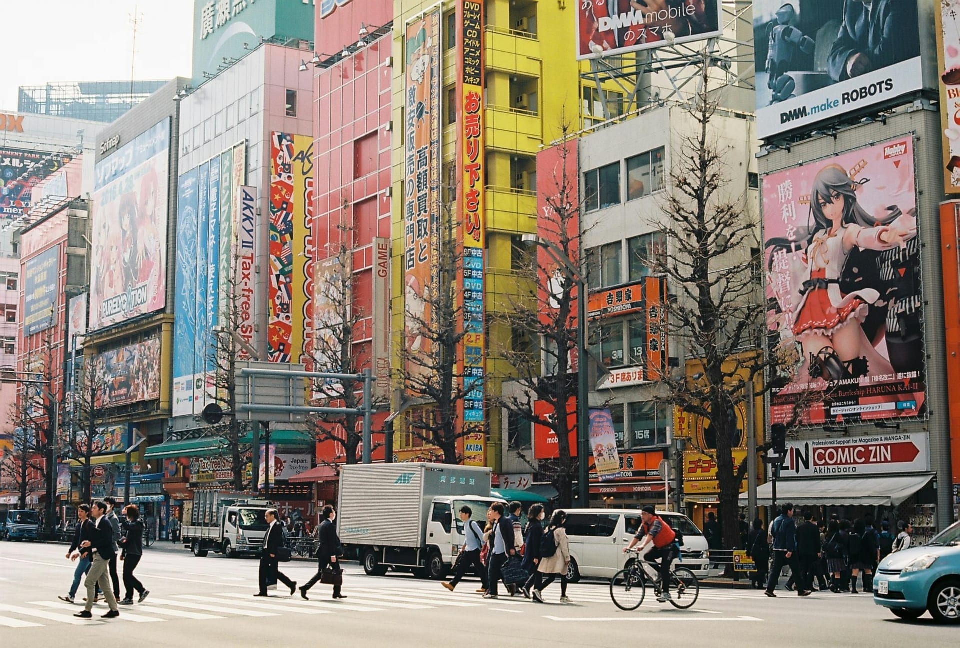 Akihabara district at night with glowing arcade signs, neon lights, and anime billboards reflecting across the busy street